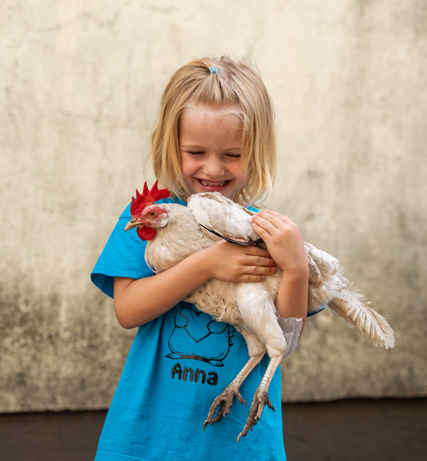 Ein lachendes Mädchen hält ein weißes Huhn im Arm