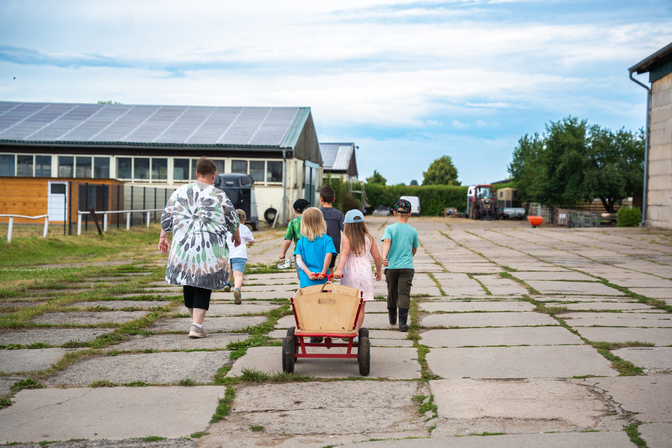 Kindergruppe zieht einen Bollerwagen über den Hofweg
